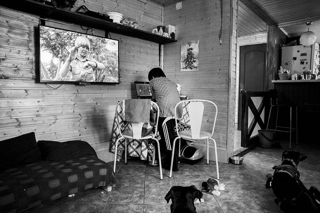 raisa mikhaylova . tanya and her kids. Vanya in the living room playing on mom’s laptop. Josi (in the right corner) can’t walk because of the intervertebral hernia paralyzed hind legs, but she moves crawling around quite deftly