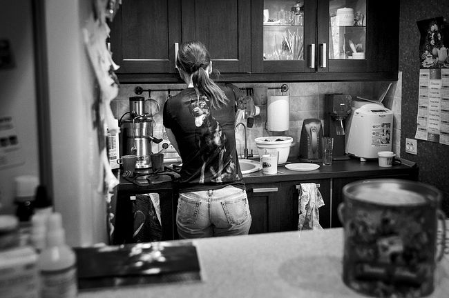 raisa mikhaylova . tanya and her kids. Tanya is washing the dishes. On her T-shirt there is a portrait of her favorite pet Caesar